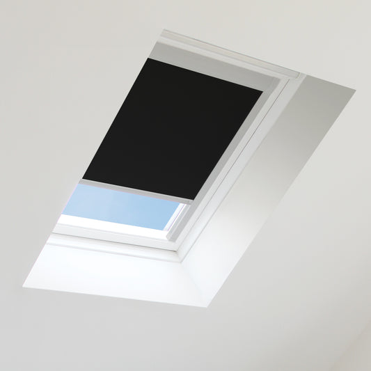 Black window blind on a skylight with a clear blue sky visible